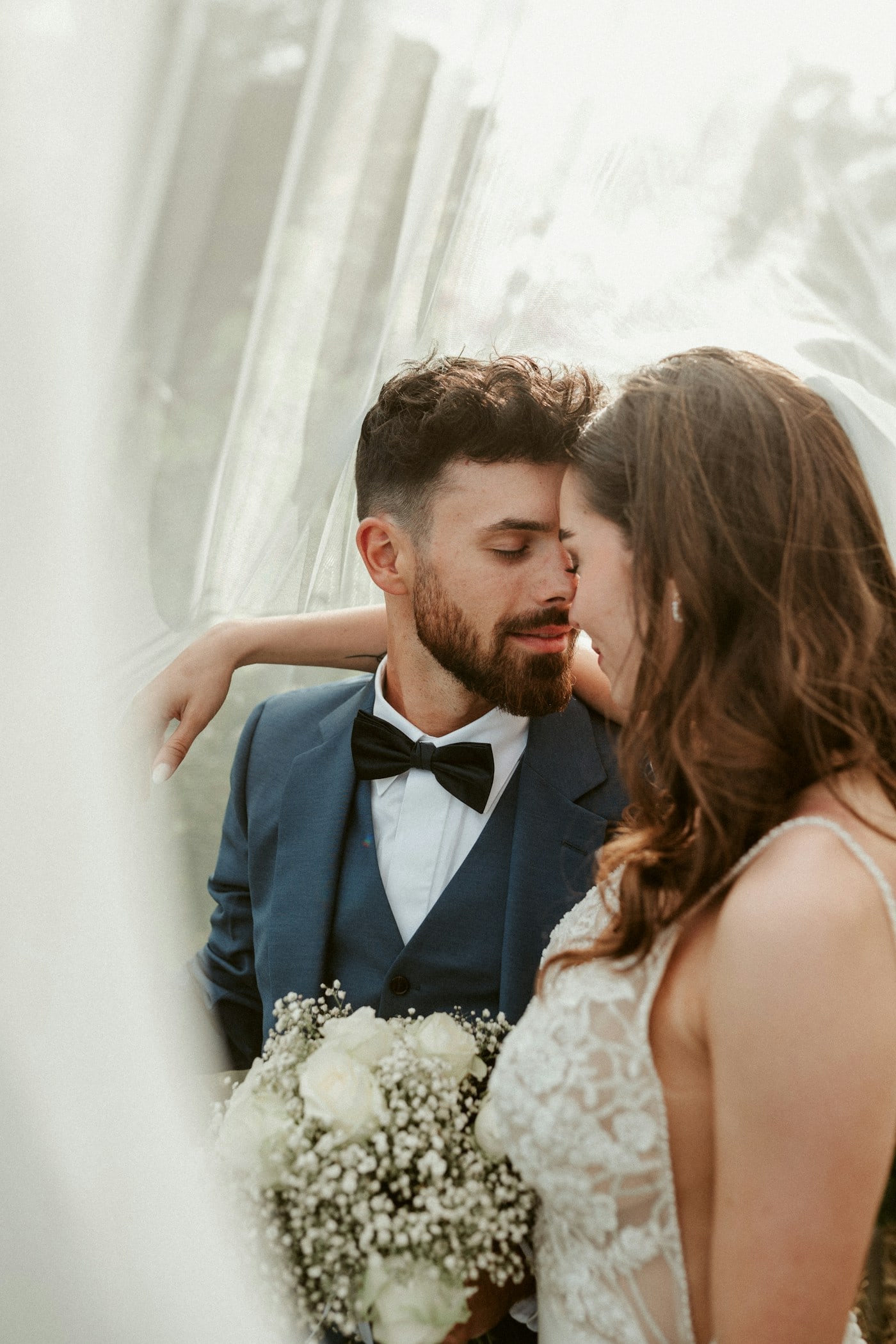 Brautpaar in eleganter Hochzeitskleidung im natürlichen Fensterlicht