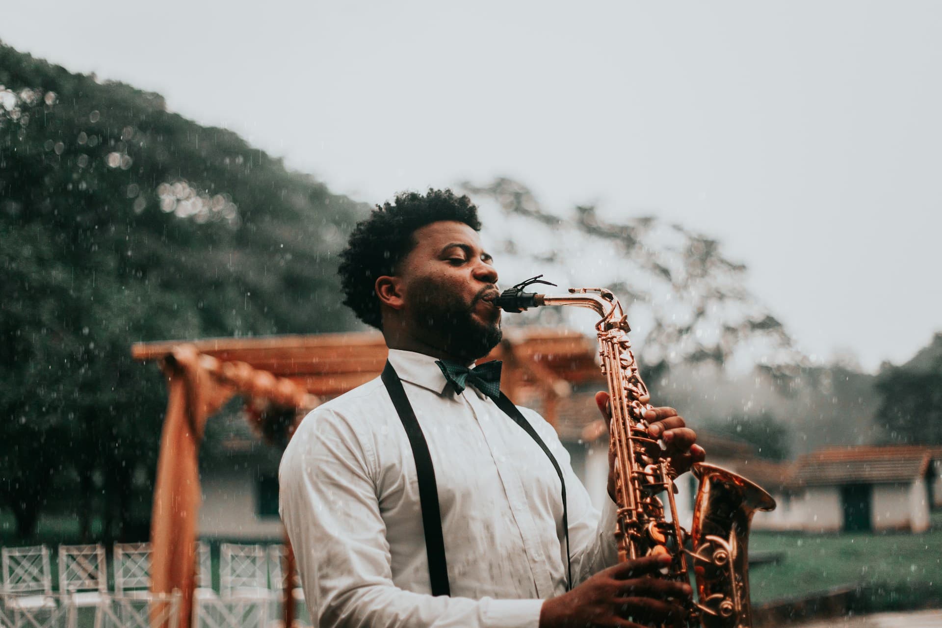 Junger Saxophonist mit Fliege und Hosenträgern bei einem Auftritt im Freien